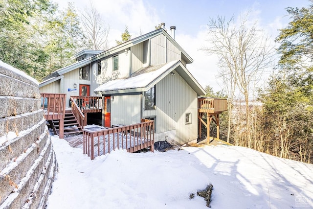 snow covered house featuring a deck and stairs