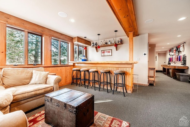 living room with a bar, recessed lighting, baseboards, carpet, and wood walls