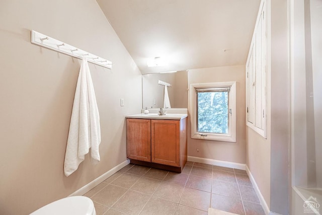 bathroom with vanity, tile patterned floors, toilet, baseboards, and lofted ceiling