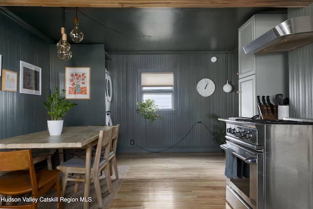 kitchen featuring wall chimney range hood, crown molding, stainless steel stove, light wood-type flooring, and white cabinetry