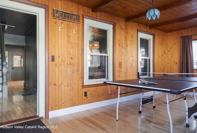 playroom with beamed ceiling, light wood-type flooring, wooden walls, and wood ceiling