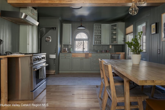 kitchen with decorative light fixtures, ventilation hood, light hardwood / wood-style flooring, and high end stainless steel range