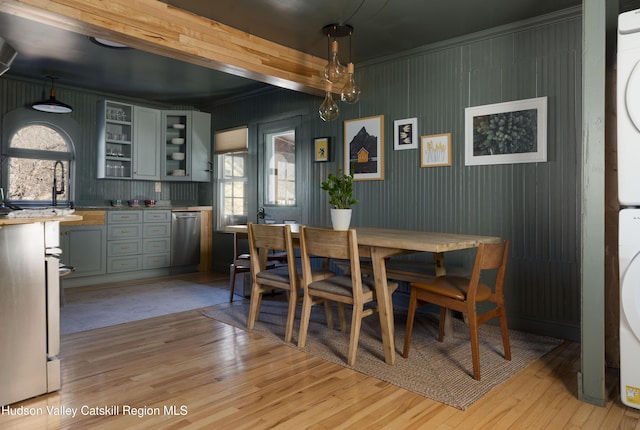 dining space featuring a wealth of natural light, crown molding, stacked washing maching and dryer, and light wood-type flooring