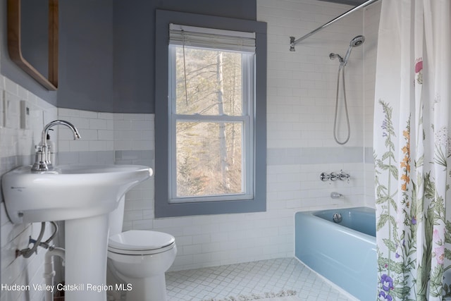 bathroom featuring tile patterned flooring, shower / bathtub combination with curtain, toilet, and tile walls