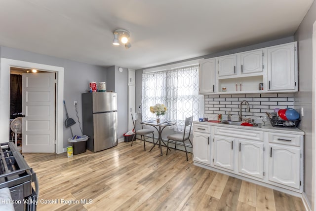 kitchen featuring baseboard heating, light wood-type flooring, a sink, and freestanding refrigerator