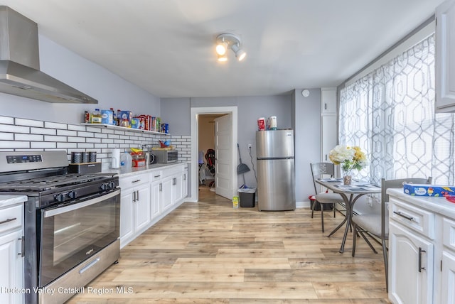 kitchen featuring light countertops, wall chimney range hood, and appliances with stainless steel finishes
