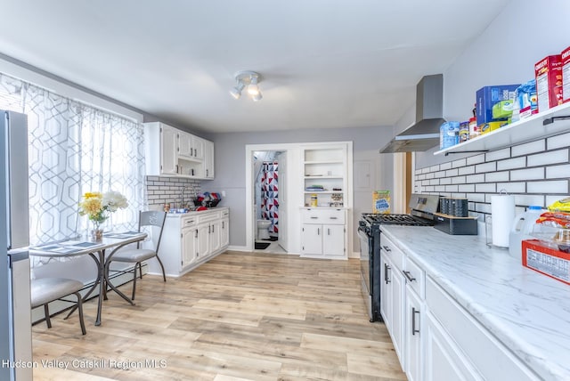 kitchen with white cabinets, wall chimney range hood, stainless steel appliances, and open shelves
