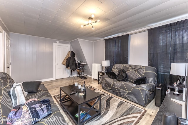 living room with radiator, crown molding, wood finished floors, and baseboards