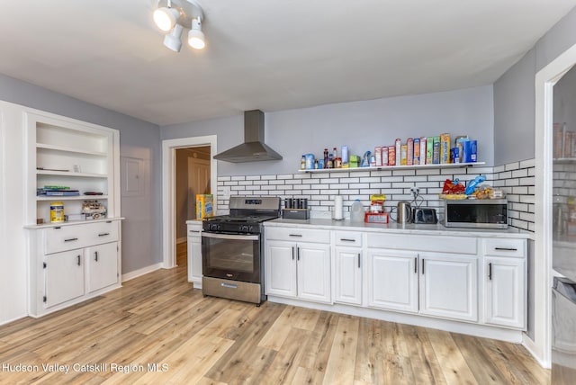 kitchen with stainless steel appliances, wall chimney exhaust hood, light wood-type flooring, and open shelves