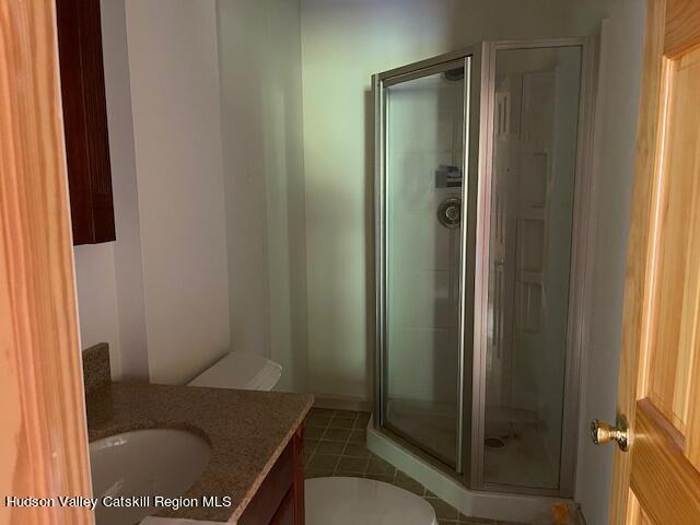 bathroom featuring tile patterned floors, vanity, toilet, and walk in shower