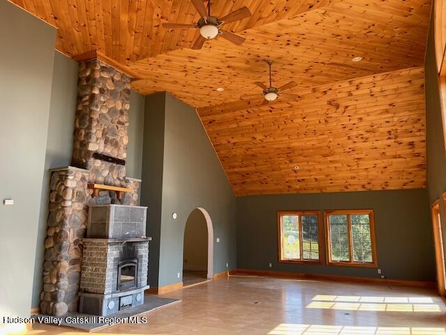 unfurnished living room with a wood stove, ceiling fan, high vaulted ceiling, and wooden ceiling