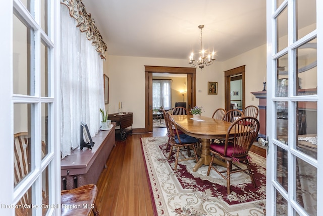 dining area featuring wood finished floors, a notable chandelier, and french doors