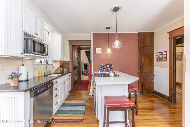 kitchen with white cabinets, appliances with stainless steel finishes, a sink, and light wood-type flooring