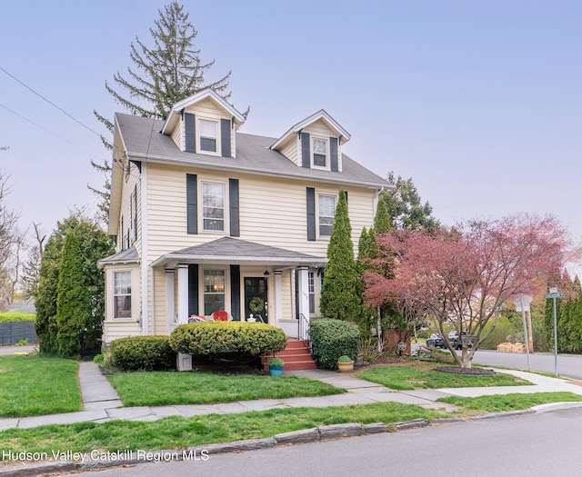 american foursquare style home with a front lawn and covered porch