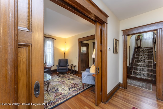 interior space featuring wood finished floors, baseboards, and stairway