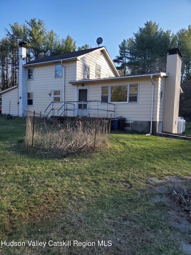 back of house featuring a yard and a chimney