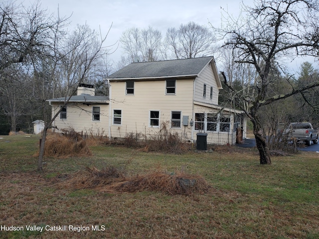 view of side of property with roof with shingles and a yard