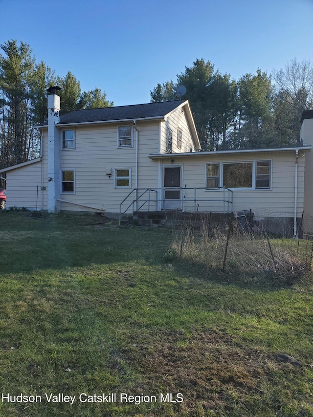 back of house featuring a yard and a chimney
