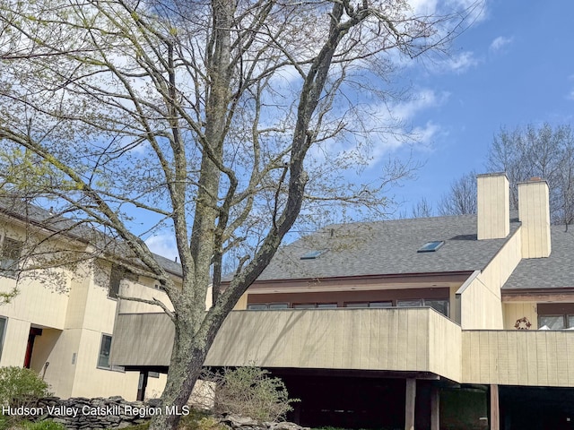 view of side of property featuring a shingled roof and a chimney