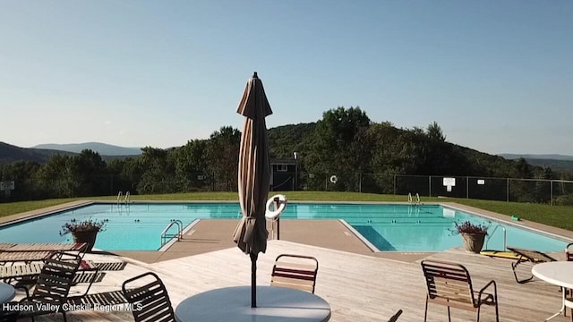 community pool with a mountain view and fence