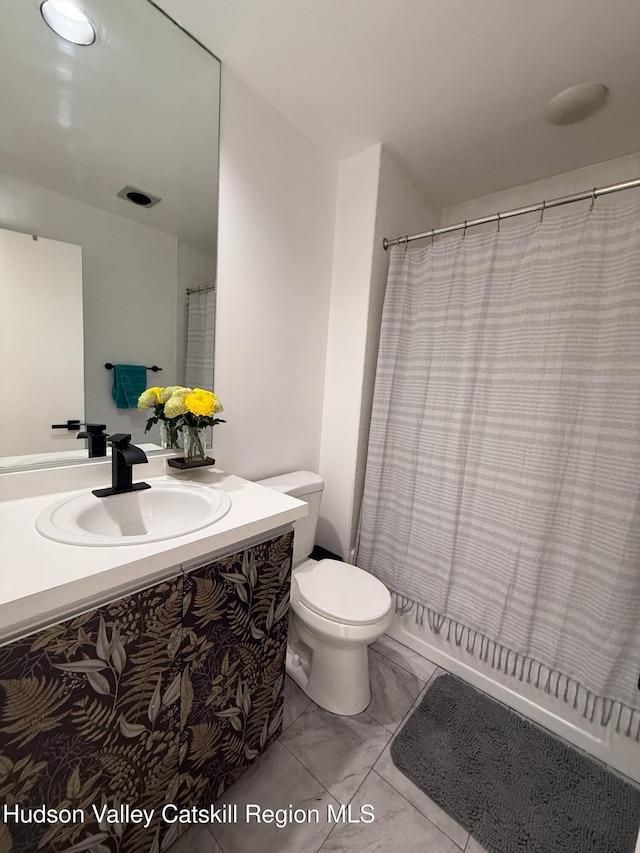 full bath with toilet, marble finish floor, and vanity