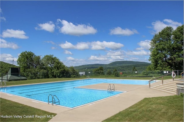 pool with fence, a mountain view, a lawn, and a patio