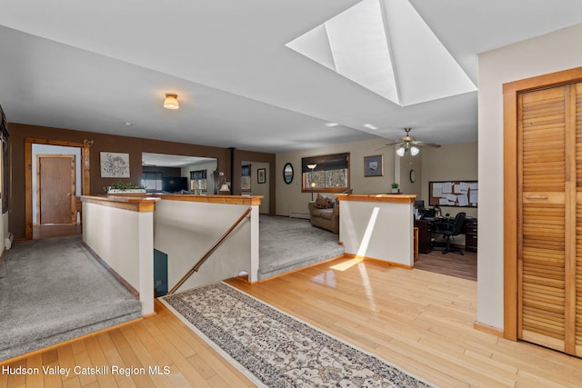 kitchen featuring a ceiling fan, a skylight, a peninsula, and light wood-style floors