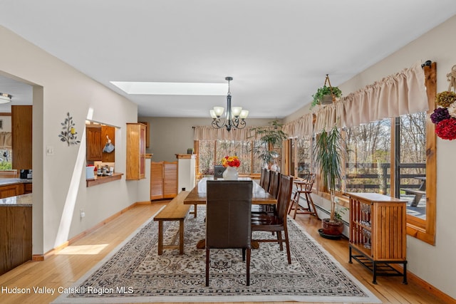 dining area featuring a wealth of natural light, a chandelier, light wood-style flooring, and baseboards