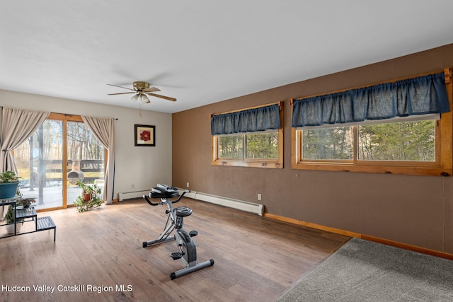 exercise room featuring baseboards, wood finished floors, a healthy amount of sunlight, and ceiling fan