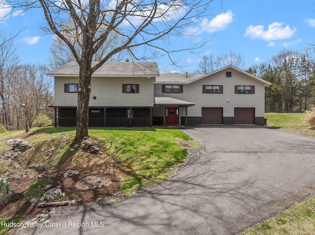 raised ranch with a front lawn, a garage, and aphalt driveway