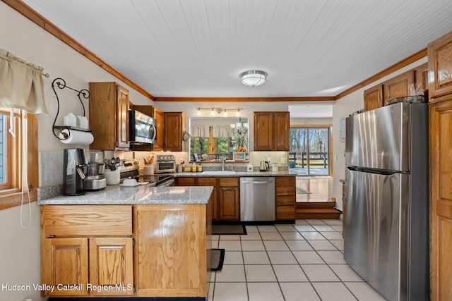 kitchen featuring light tile patterned floors, stainless steel appliances, brown cabinets, a sink, and a peninsula