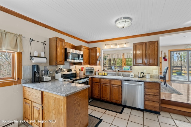 kitchen with brown cabinets, stainless steel appliances, a peninsula, and a sink