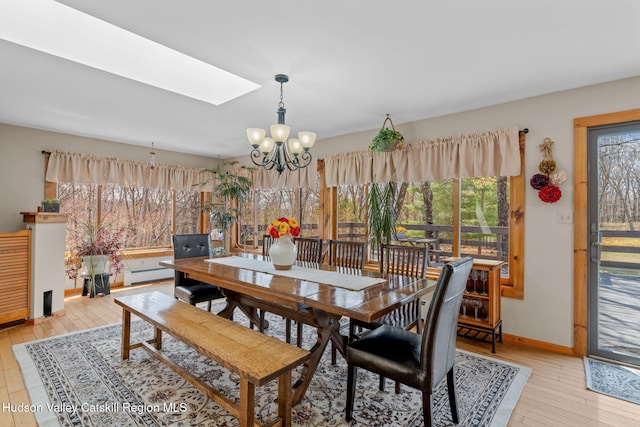 dining space featuring a chandelier, light wood-style floors, baseboards, and a skylight