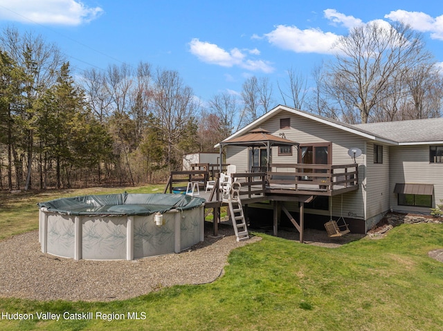 back of property with a covered pool, a lawn, roof with shingles, a deck, and a gazebo