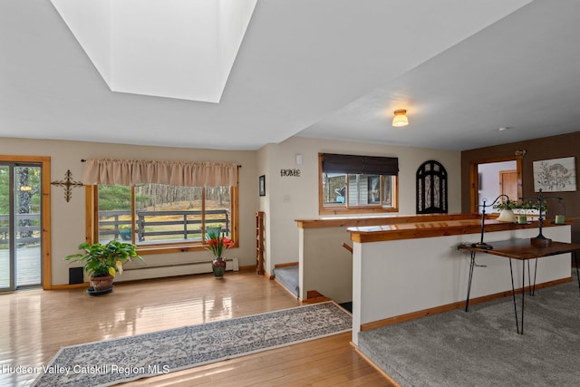 interior space featuring baseboards, wood finished floors, a baseboard heating unit, and a skylight