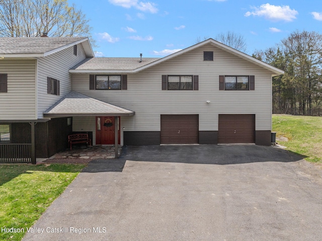 view of front of house with an attached garage, aphalt driveway, and roof with shingles