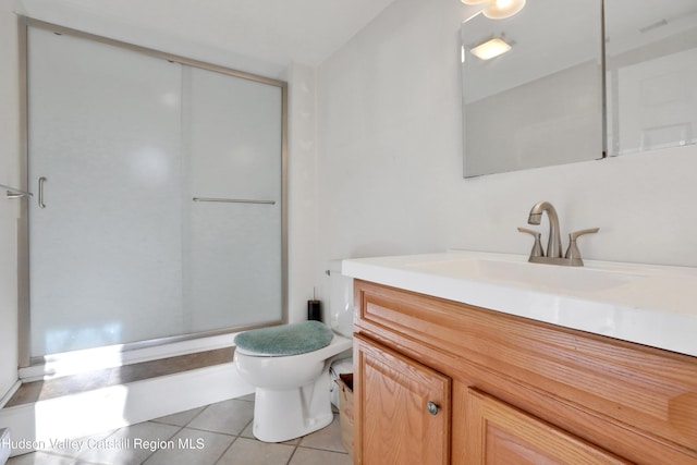 bathroom featuring toilet, vanity, tile patterned floors, and a shower with shower door