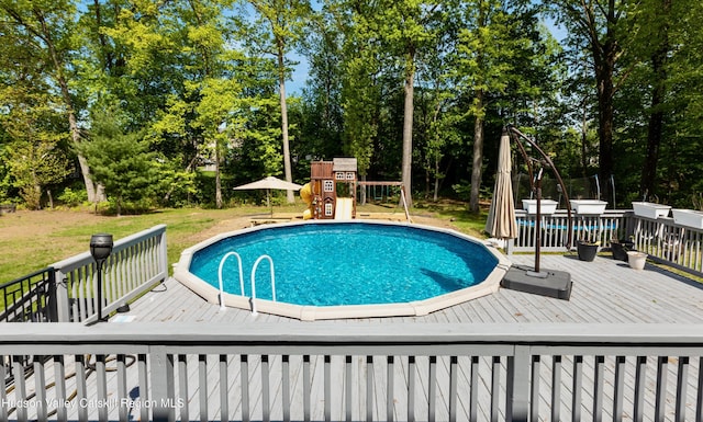 33 Camelot Ct, Saugerties, NY 12477 - swimming pool with a wooden deck, view of wooded area, and a playground