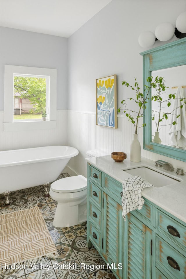 14 Bushnell Ave, Chatham, NY 12037 - bathroom with a wainscoted wall, a freestanding bath, vanity, tile patterned flooring, and toilet