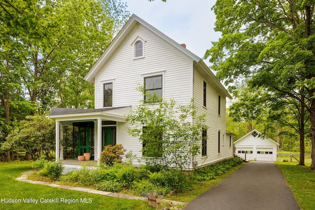 14 Bushnell Ave, Chatham, NY 12037 - view of front facade featuring an outdoor structure, a chimney, a detached garage, and a front yard