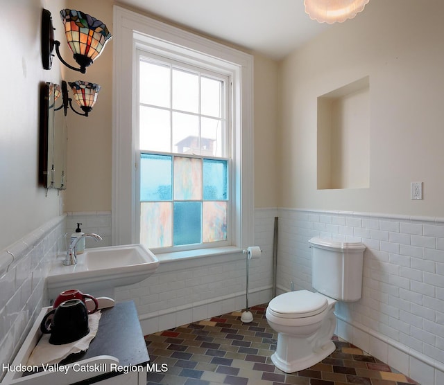 230 Warren St, Hudson, NY 12534 - bathroom with tile walls, wainscoting, toilet, plenty of natural light, and a sink