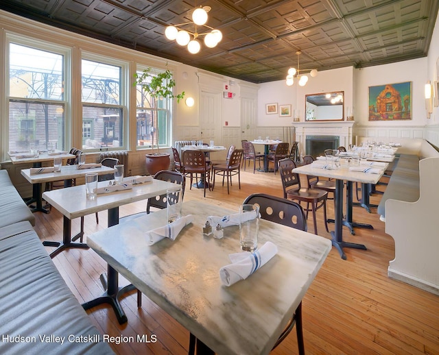 230 Warren St, Hudson, NY 12534 - dining room featuring an ornate ceiling, a fireplace, a wainscoted wall, a chandelier, and light wood-type flooring
