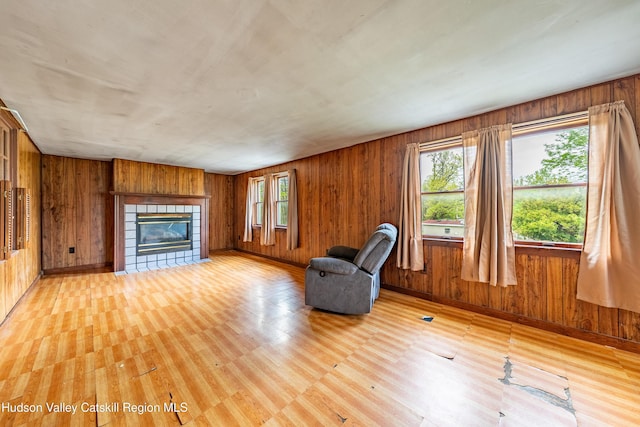 334 Joslen Blvd, Hudson, NY 12534 - unfurnished living room featuring a tiled fireplace, light wood finished floors, wooden walls, and baseboards