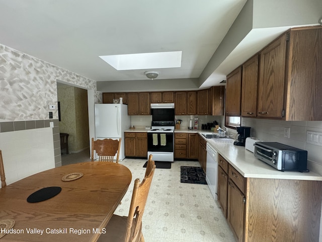 kitchen featuring sink, white appliances, and a skylight