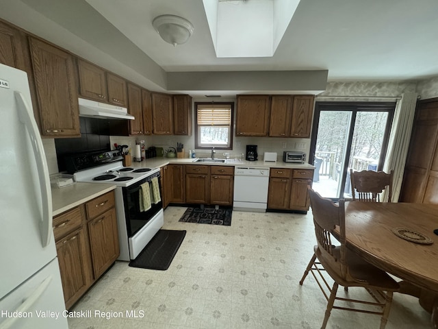 kitchen featuring white appliances, sink, and backsplash