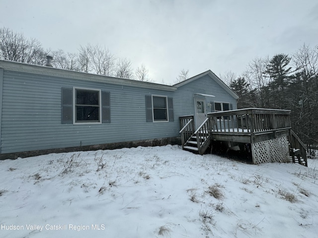 snow covered back of property featuring a deck