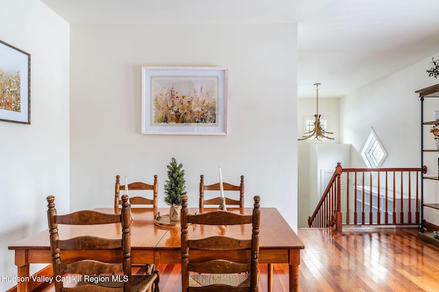 dining space with hardwood / wood-style floors and a notable chandelier