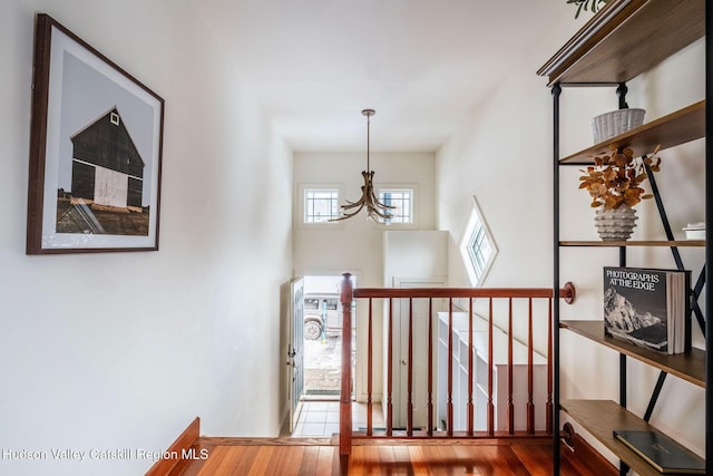 hallway featuring wood-type flooring and an inviting chandelier