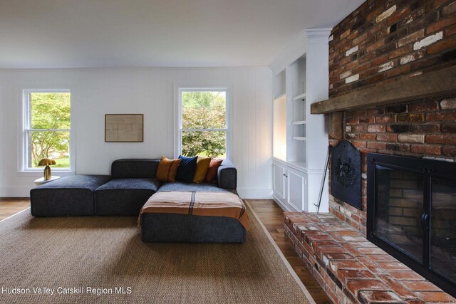 living room featuring hardwood / wood-style flooring, built in features, a fireplace, and ornamental molding