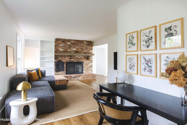 living room with a fireplace, built in features, and hardwood / wood-style flooring